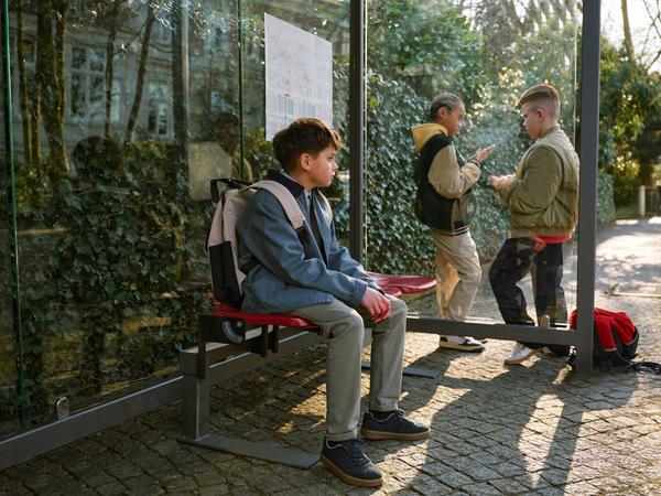 Junge beobachtet andere Kinder, die ein Smartphone haben