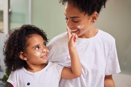 Mutter und Tochter cremen sich ihr Gesicht ein