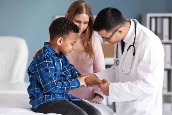 Arzt untersucht den Arm eines kleinen Jungen