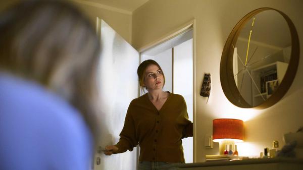 Mutter schaut ins Kinderzimmer und sieht einen zersprungenen Spiegel an der Wand